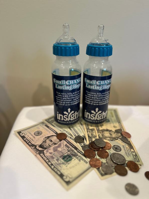 Two baby bottles beside a pile of bills and coins ready to be counted