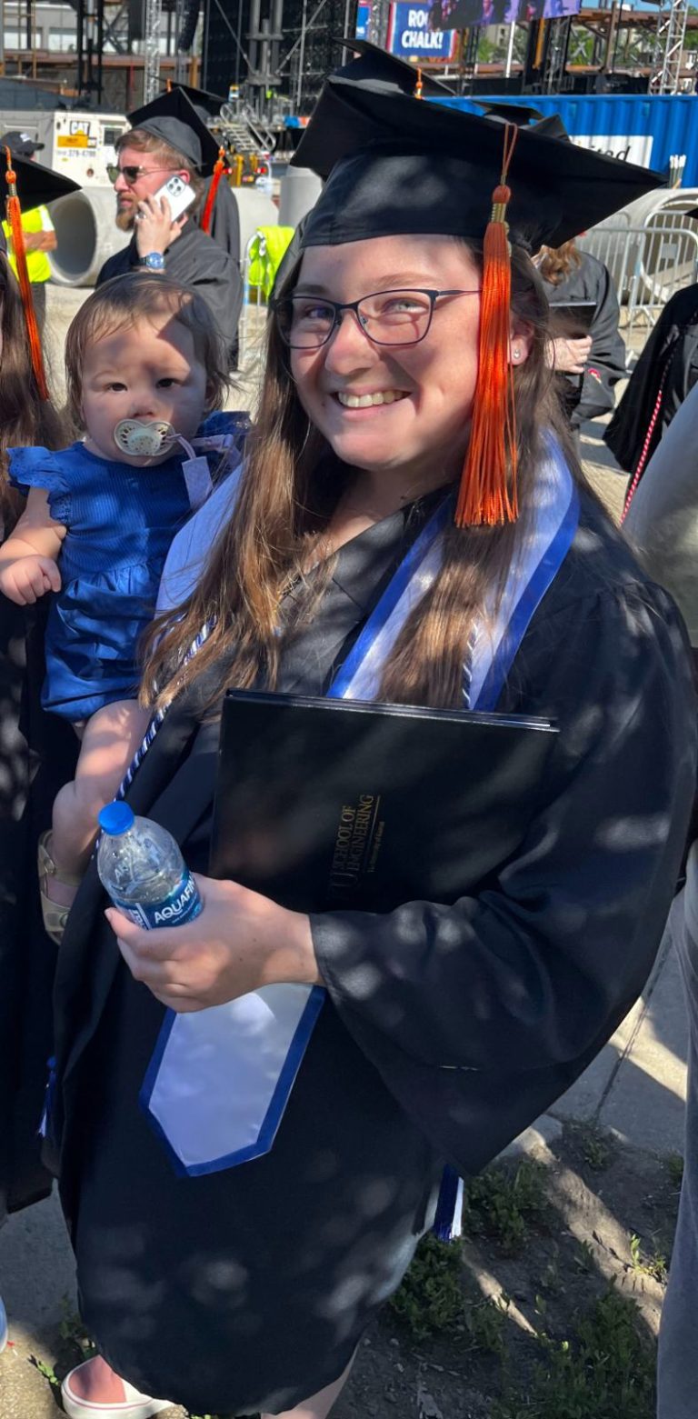 Graduate in cap and gown holding her baby daughter
