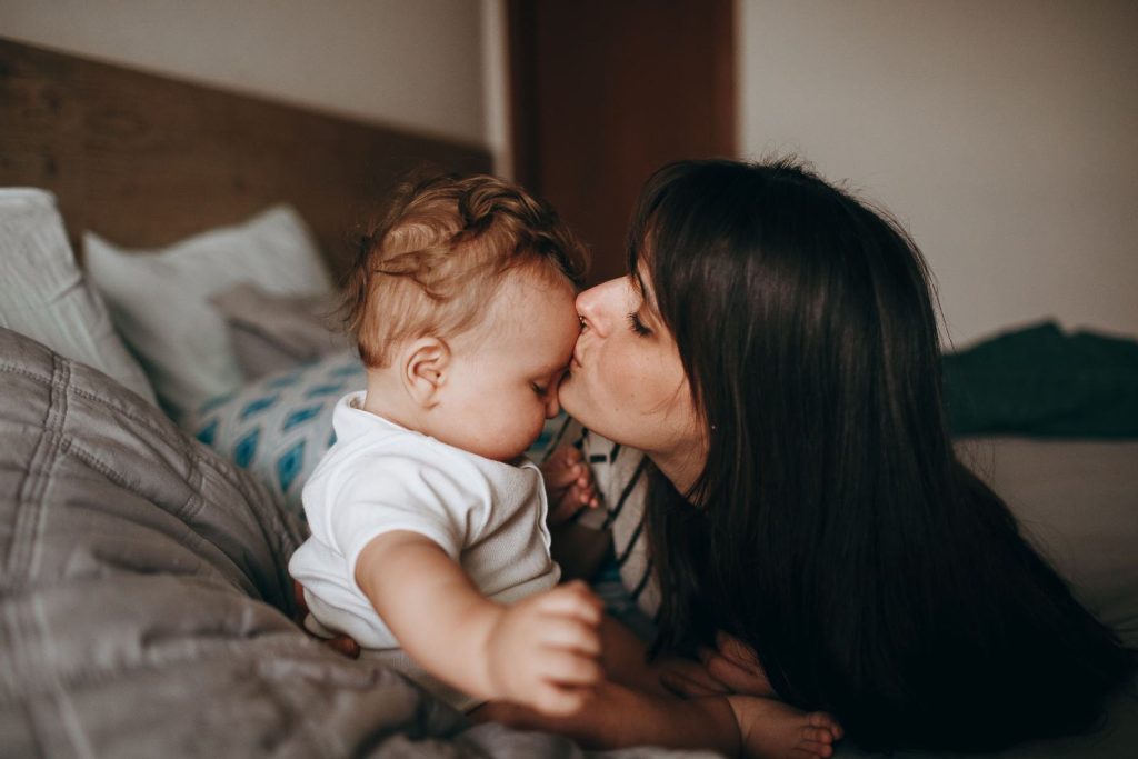 Mother kissing her baby’s forehead at home